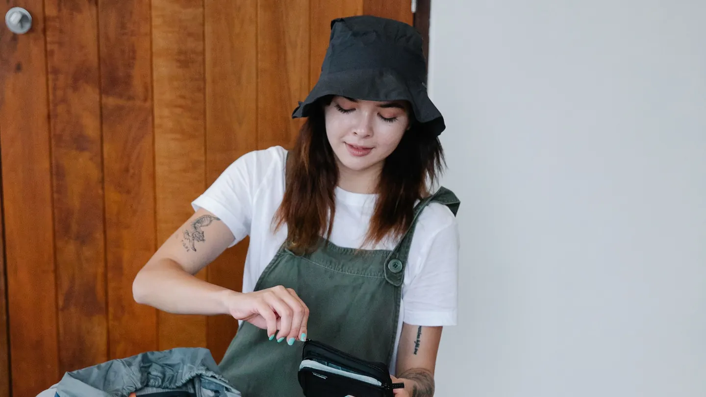 A traveler prepares her backpack and gear before a camping trip.